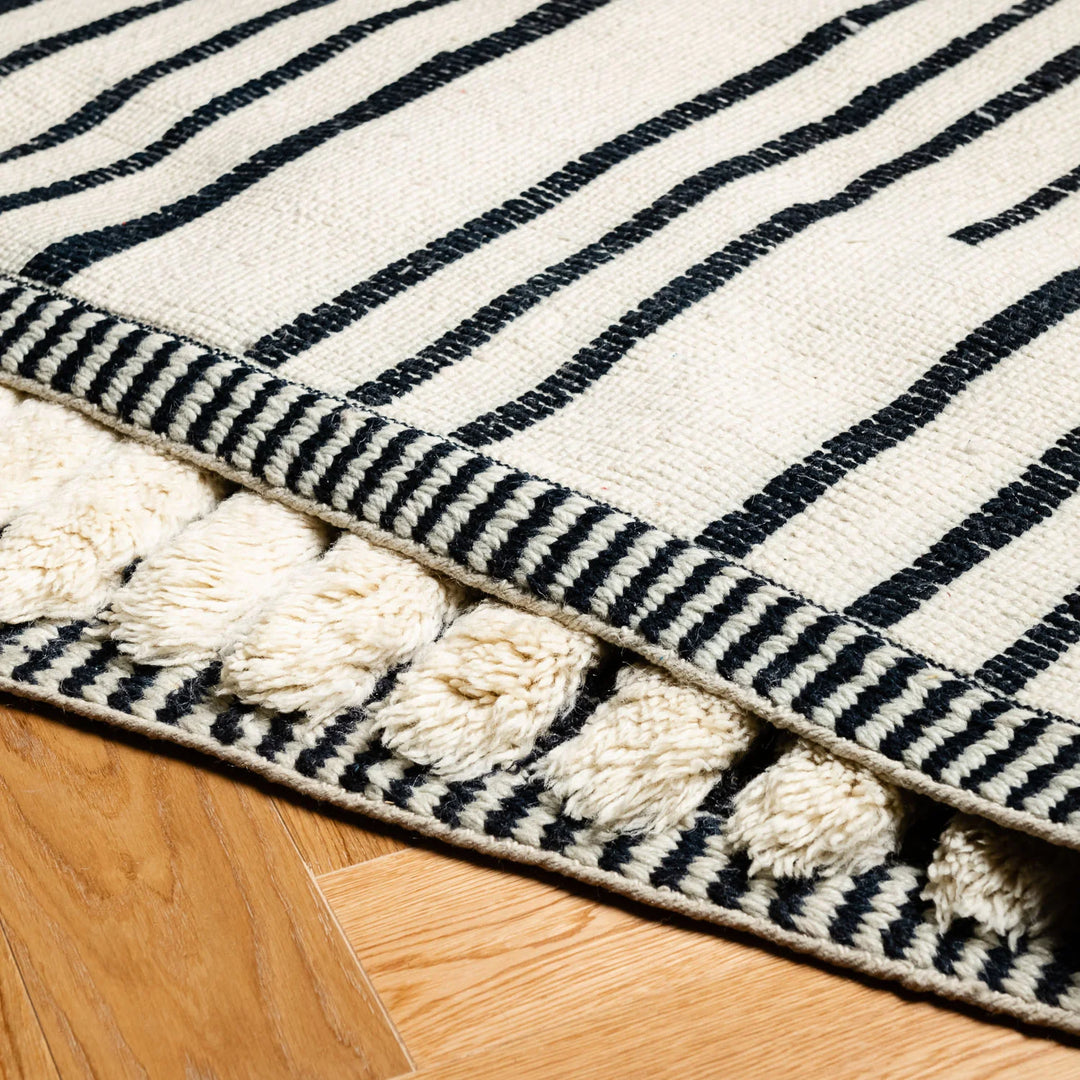 Close-up of a handmade Moroccan striped rug with thick pile, showcasing traditional Berber weaving and natural wool.