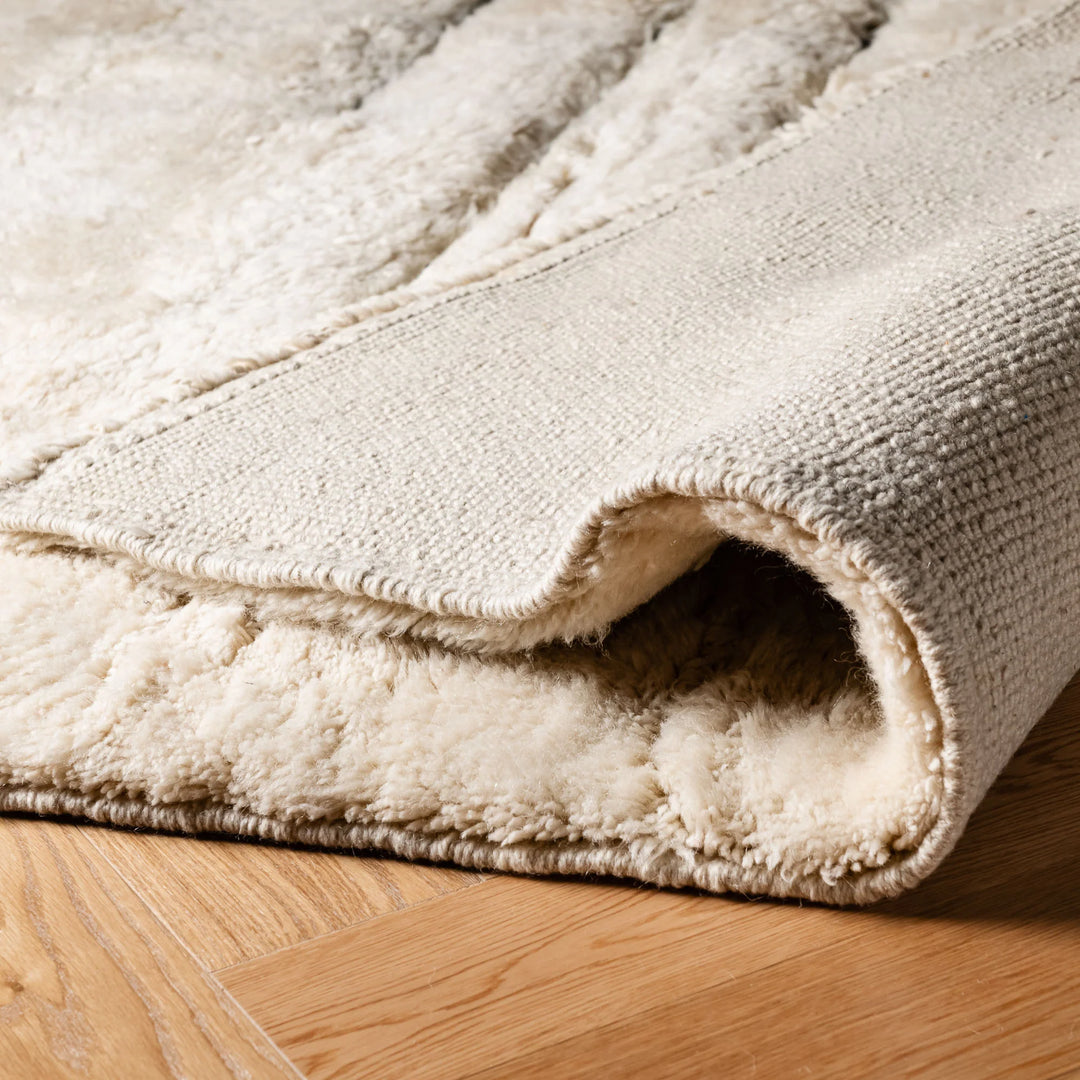 Close-up of folded luxurious Moroccan wool rug showcasing soft texture and craftsmanship.
