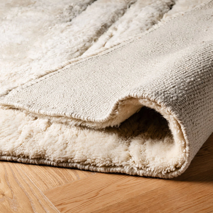 Close-up of folded luxurious Moroccan wool rug showcasing soft texture and craftsmanship.