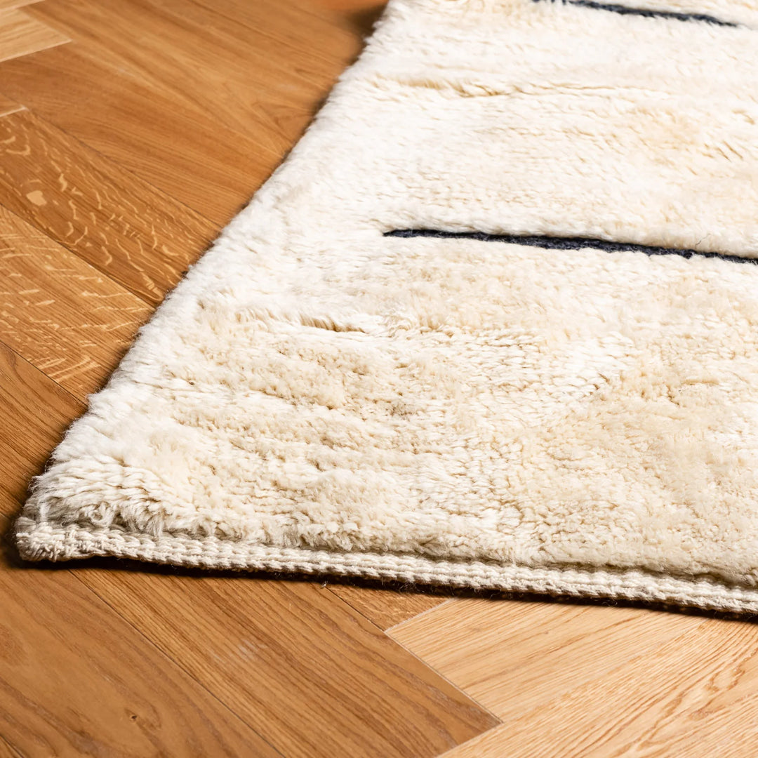Minimalist Beni Ourain cream rug with black stripes, handmade Moroccan wool rug for Scandinavian or boho interiors.