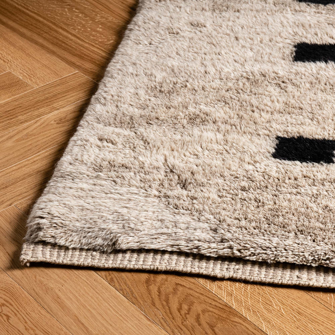Close-up of a minimalist checkered Moroccan Berber wool rug on wooden floor, showcasing its soft texture and modern design.
