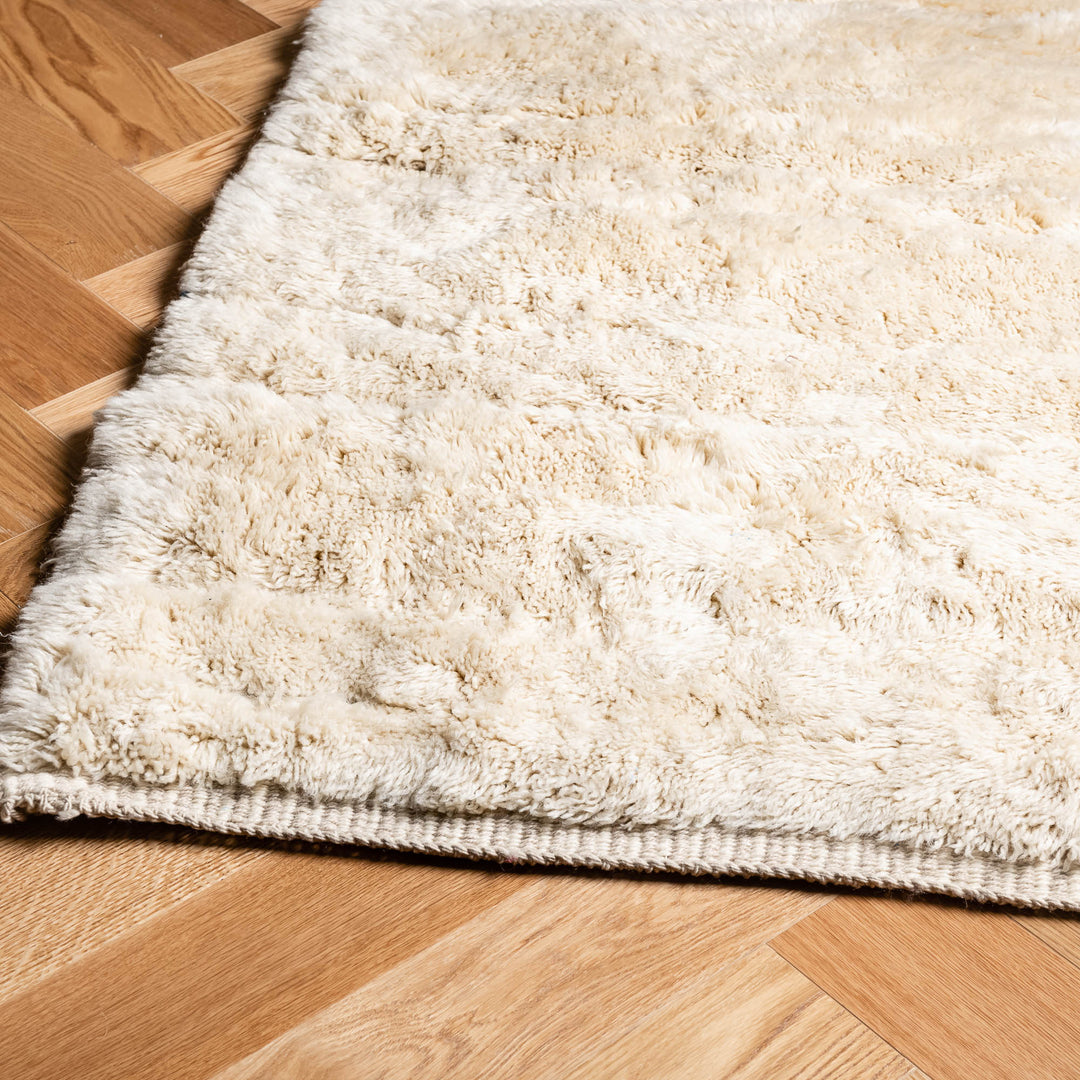 Minimalist Cream Beni Mrirt Moroccan wool rug, showcasing plush texture and traditional Berber design on wooden floor.