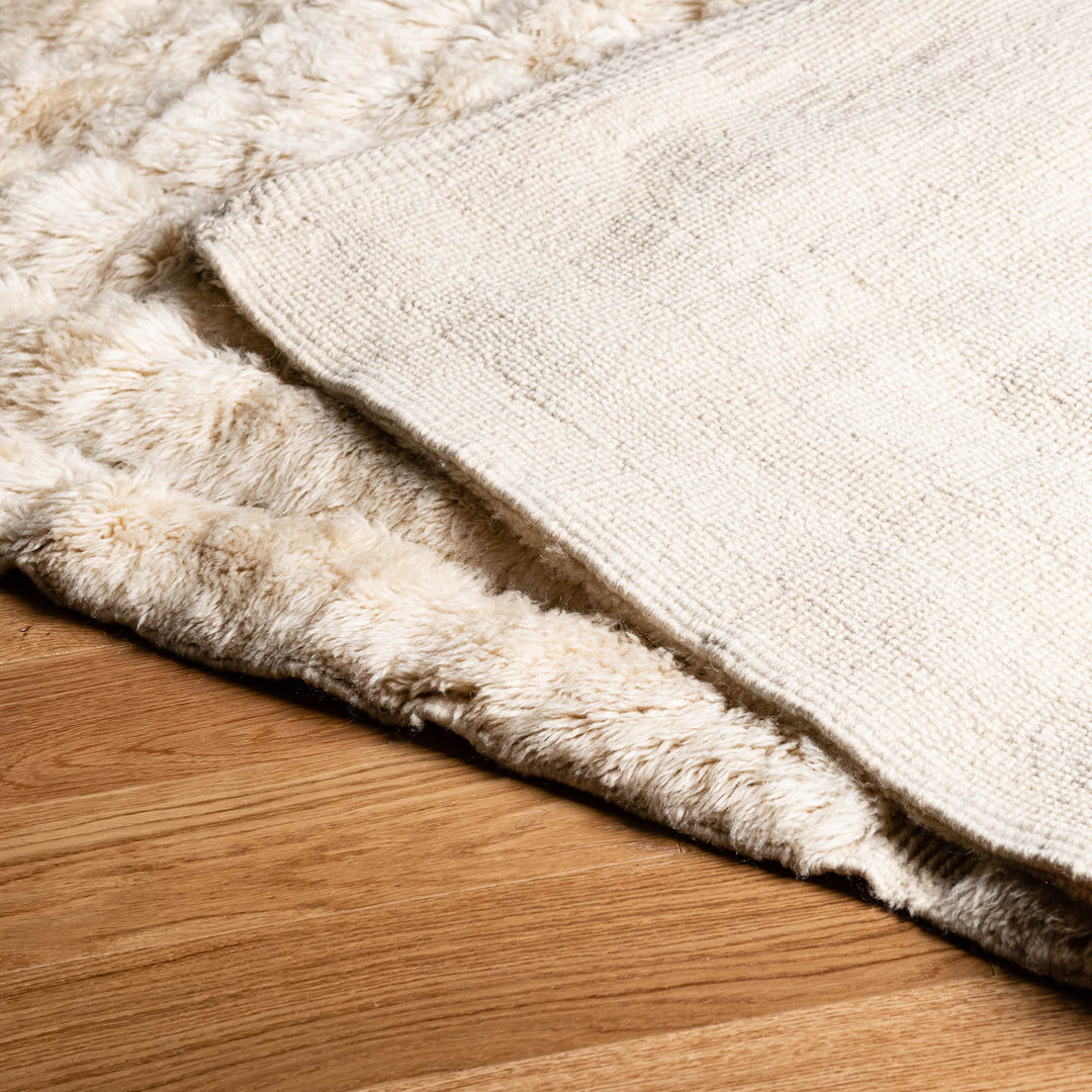 Minimalist Moroccan wool rug on wooden floor, showcasing soft texture and geometric design ideal for modern interiors.