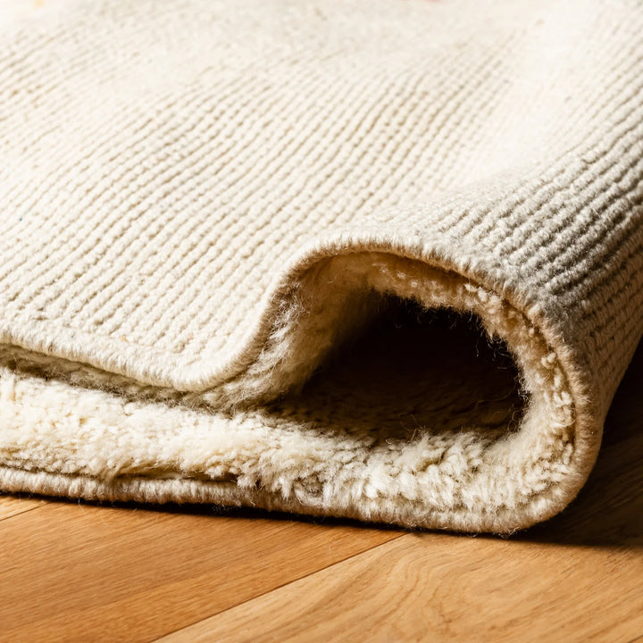 Close-up of a folded minimalist Moroccan wool rug showcasing thick, plush texture. Perfect for modern, earthy decor styles.