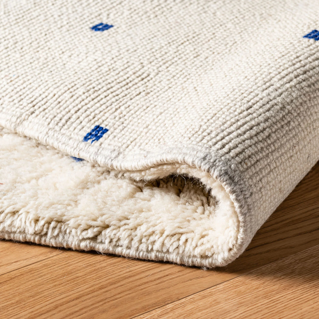 Close-up of a handcrafted Moroccan wool rug with blue accents, showcasing plush texture and intricate design.