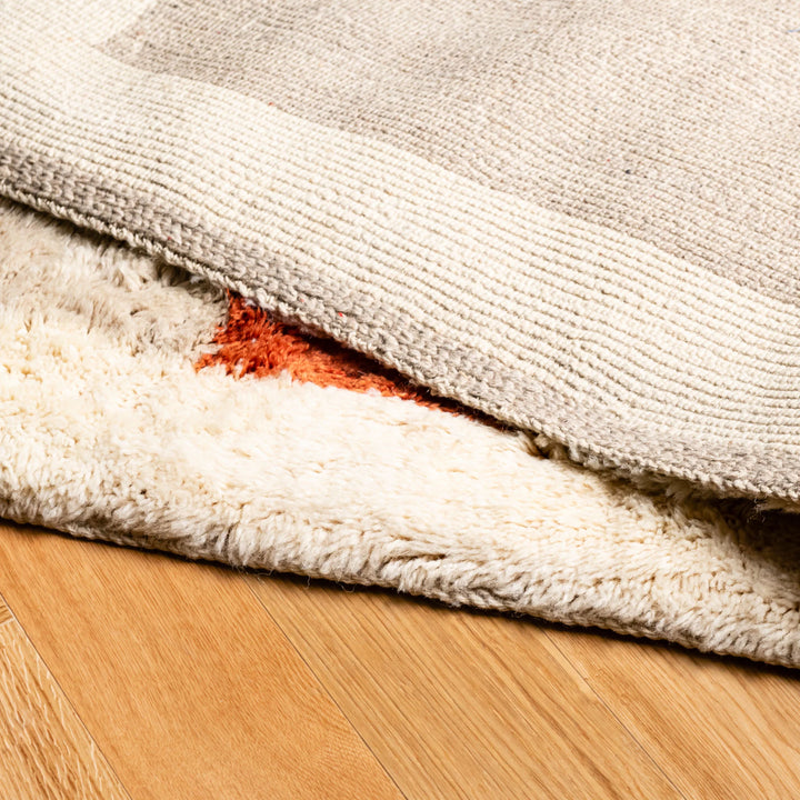 Close-up of Moroccan wool rug with terracotta and ochre tones, showcasing plush texture and handmade craftsmanship.