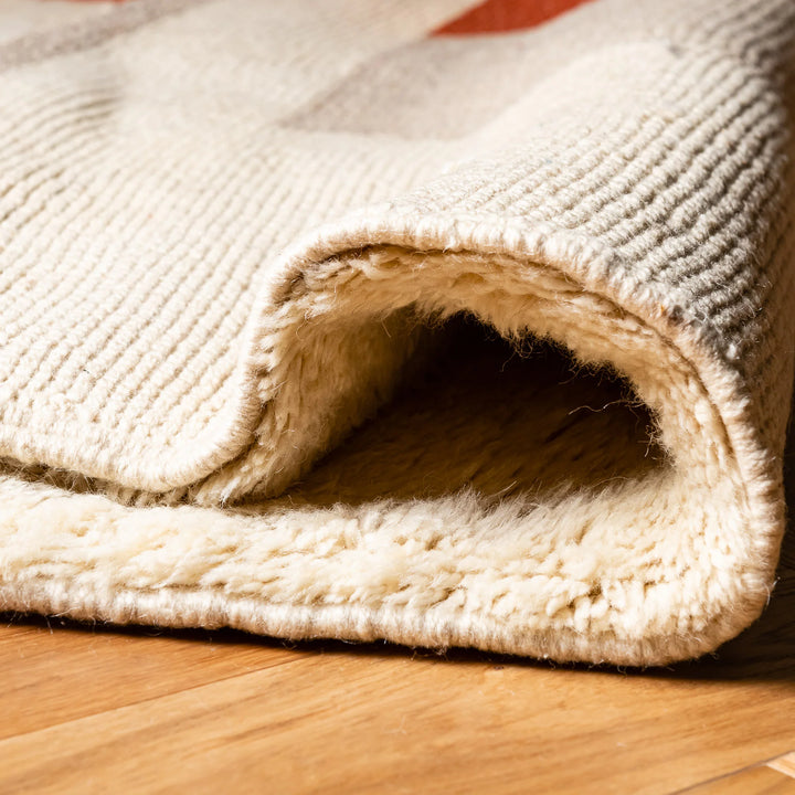 Close-up of plush Moroccan wool rug with terracotta and ochre tones, showcasing texture and craftsmanship. Ideal for modern interiors.