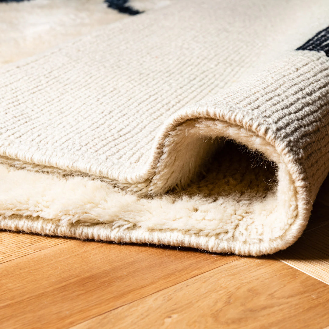 Modern Beni Mrirt Moroccan wool rug with black abstract lines on a wooden floor, showcasing craftsmanship and texture.