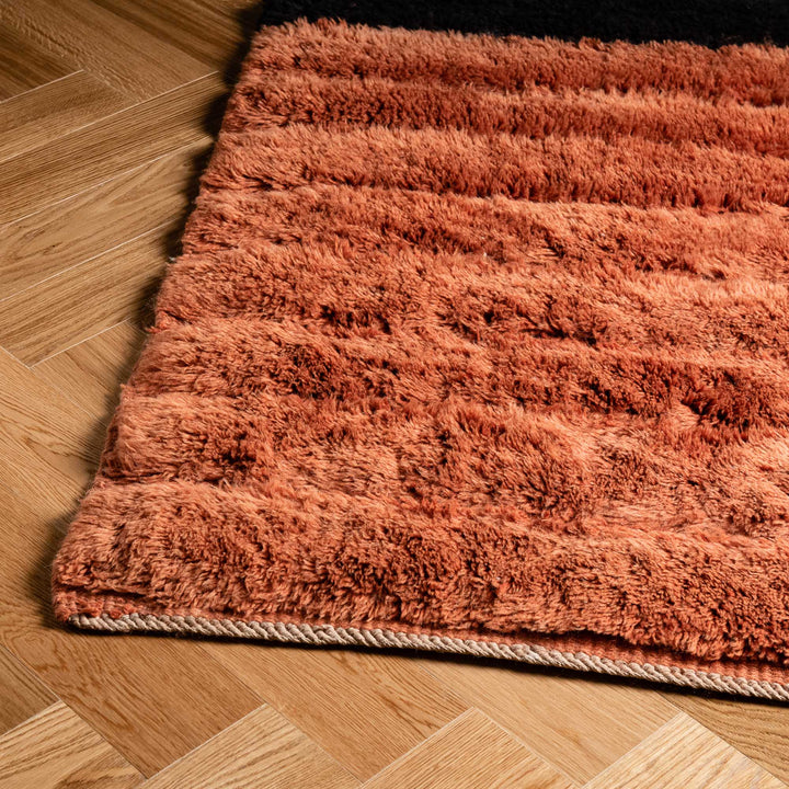 Black and rust handmade Moroccan Beni Mrirt wool rug on wooden floor, showcasing traditional Berber design.