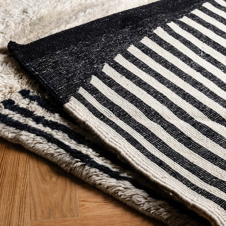 Black and white striped Moroccan wool rug on hardwood floor.