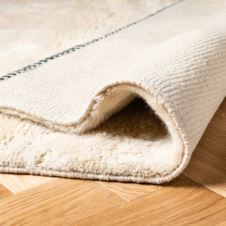 Modern Moroccan wool rug with abstract design, showcasing plush texture and natural warm tones on wooden floor.