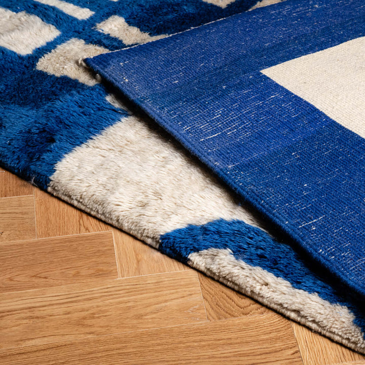 Close-up of a Modern Moroccan Rug showcasing blue and white geometric abstract design, highlighting artisan craftsmanship and wool texture.