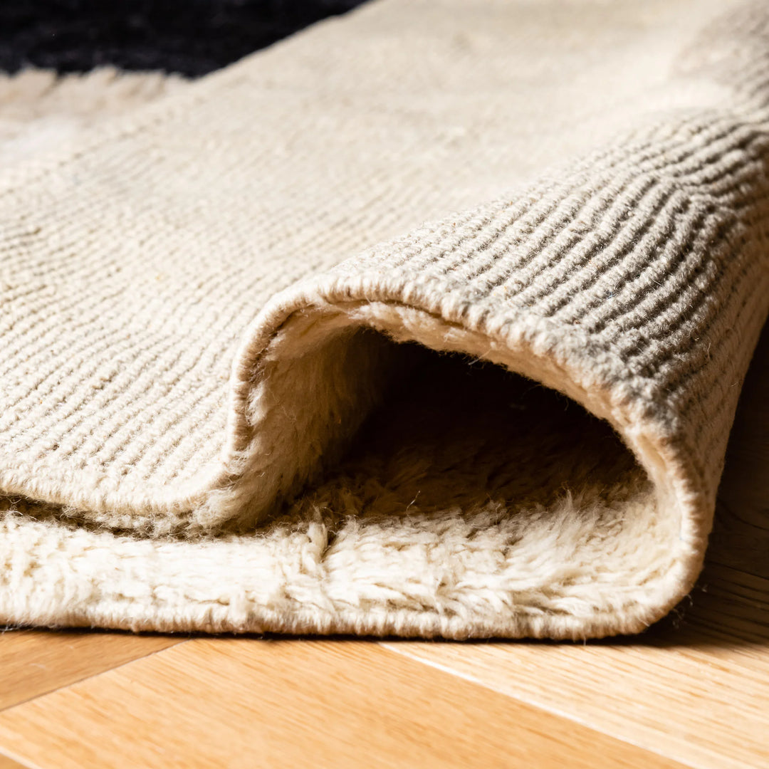 Close-up of a handmade Modern Moroccan Wool Rug with bold black stripe and beige shapes, ideal for contemporary spaces.