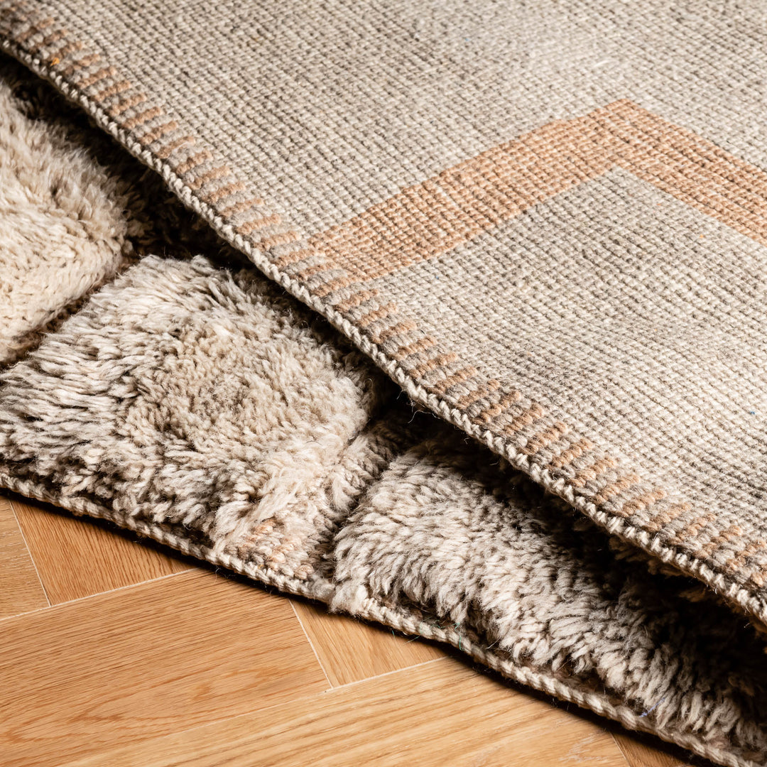 Neutral Moroccan wool rug with abstract Berber design, showcasing beige tones and geometric pattern on hardwood floor.
