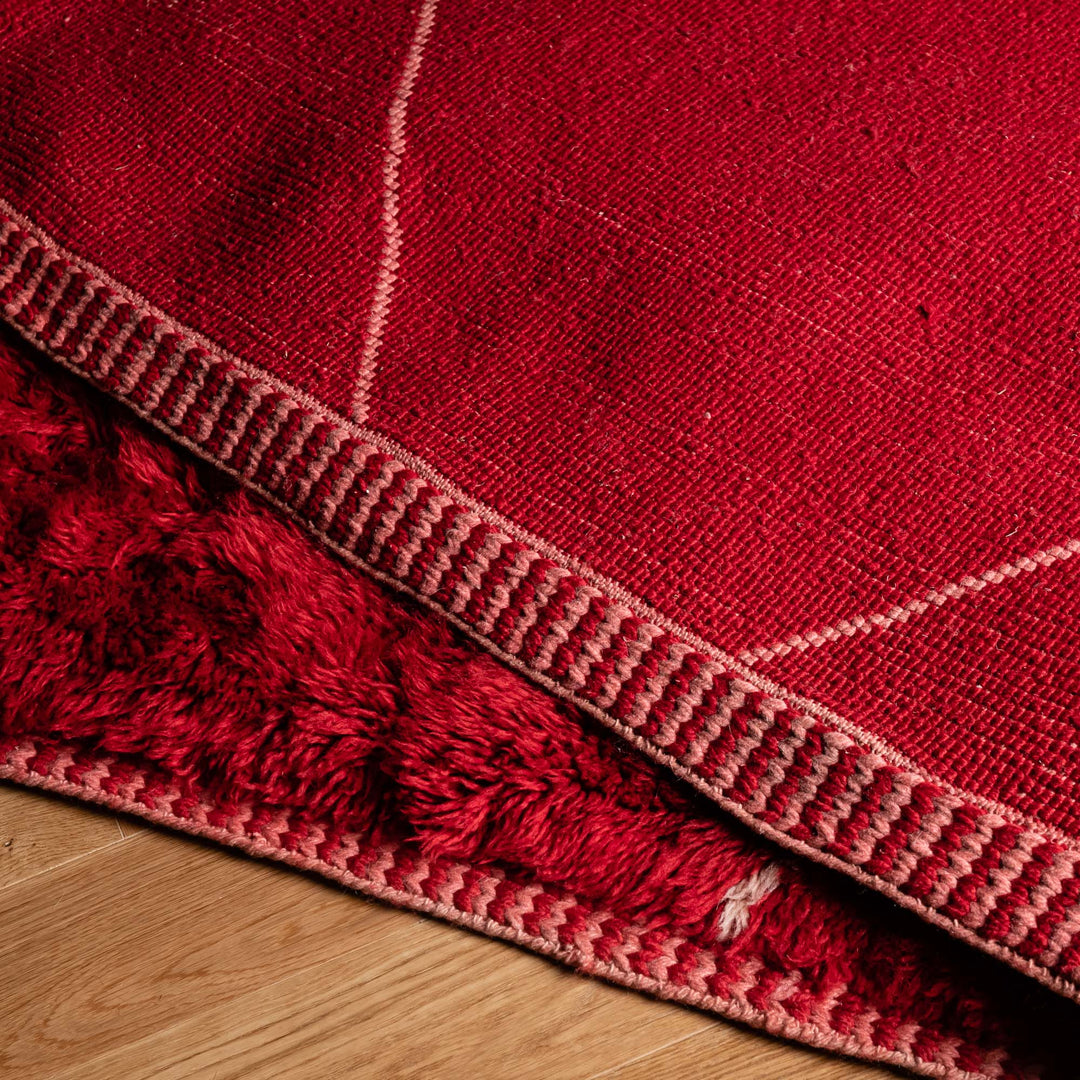 Red Beni Mrirt handmade Moroccan wool rug with white diamond pattern on wood floor.
