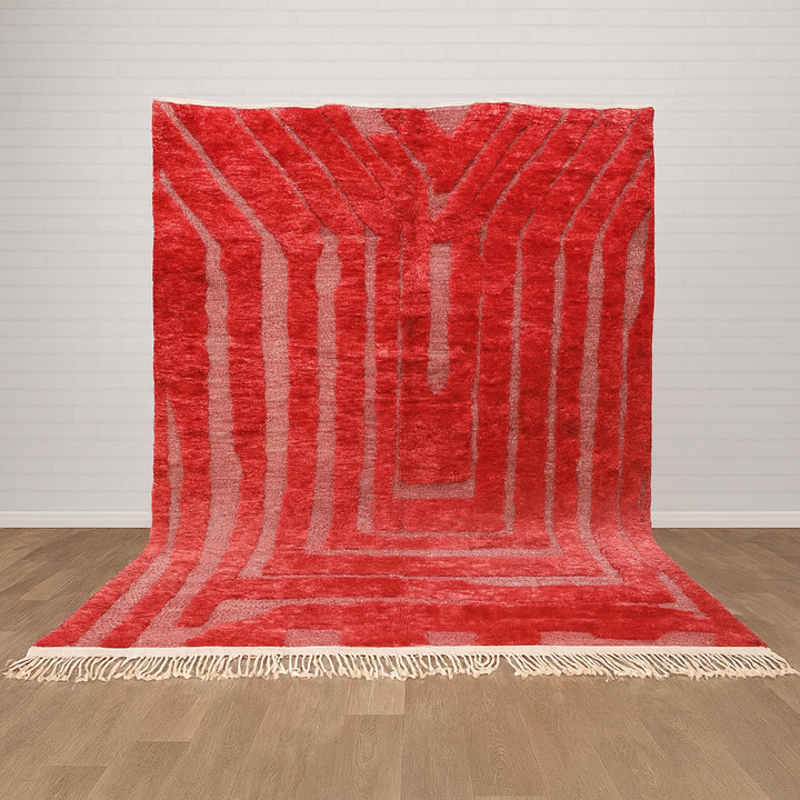 Red textured rug with white fringe on a wooden floor and light gray wall background