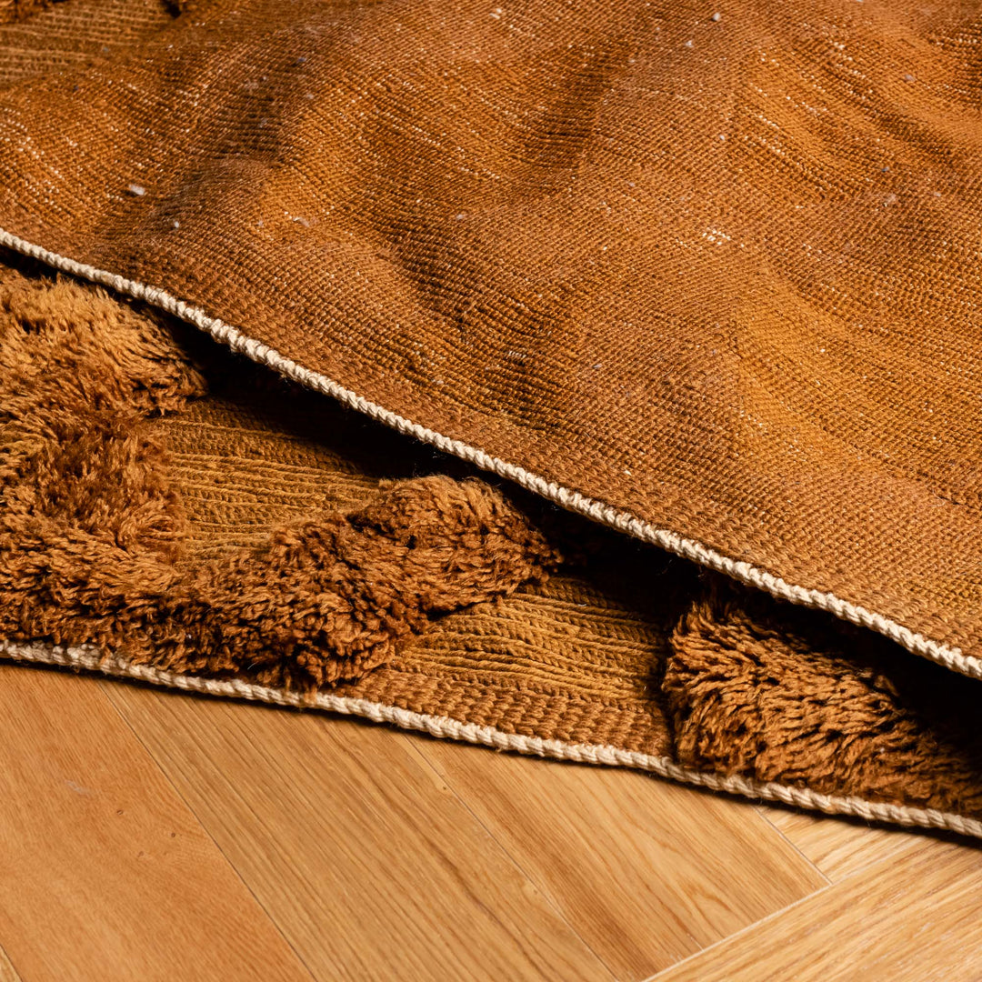 Close-up of Rust Brown Moroccan Beni Mrirt Rug with diamond design, crafted from plush, hand-knotted Moroccan wool on hardwood floor.