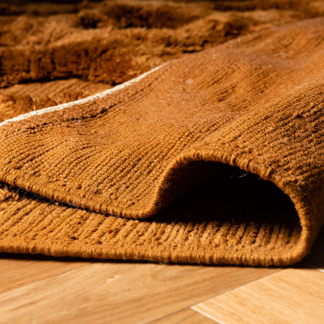 Close-up of a rust brown Moroccan Beni Mrirt wool rug with a diamond design on a wooden floor, showcasing plush texture and intricate patterns.