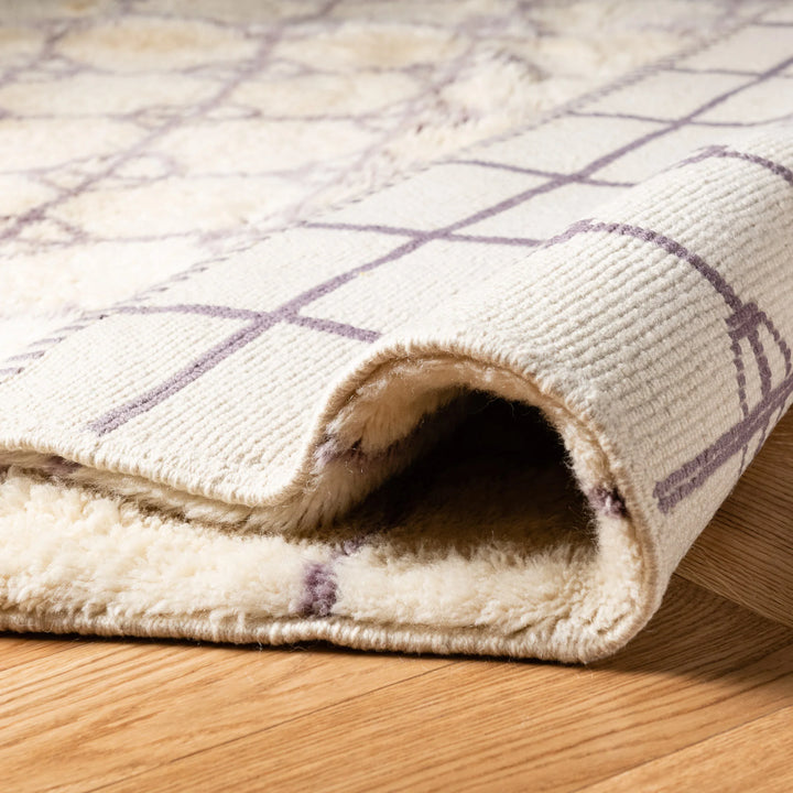 Soft Beni Ourain Moroccan rug with lavender diamond circles on a natural wool texture, rolled on wooden floor.