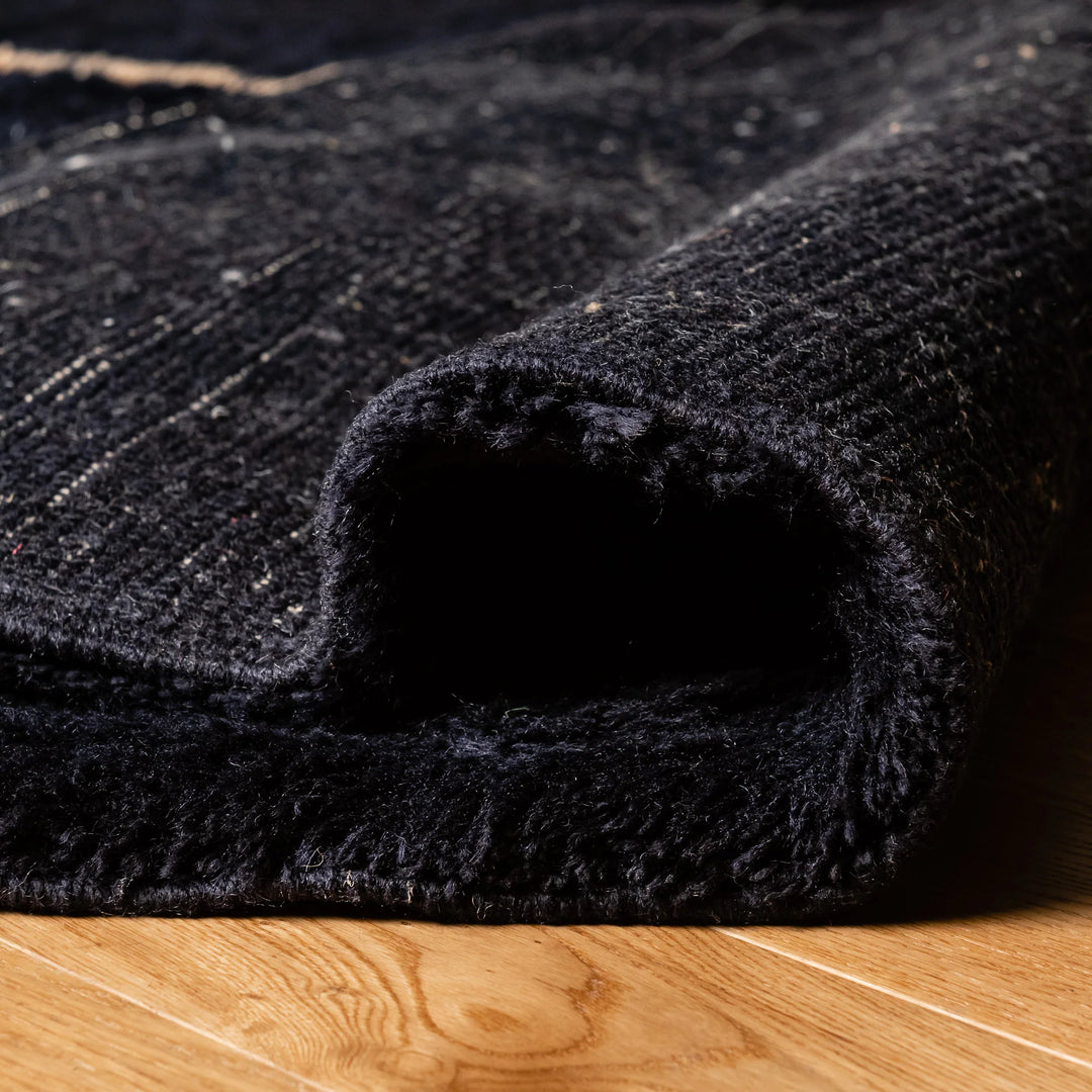 Close-up of black Moroccan wool rug, showcasing texture and craftsmanship.