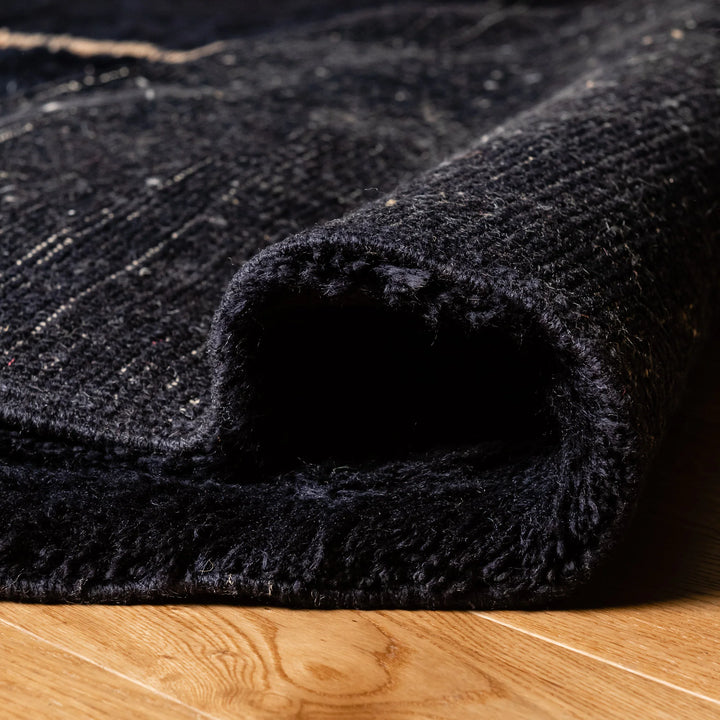 Close-up of black Moroccan wool rug, showcasing texture and craftsmanship.
