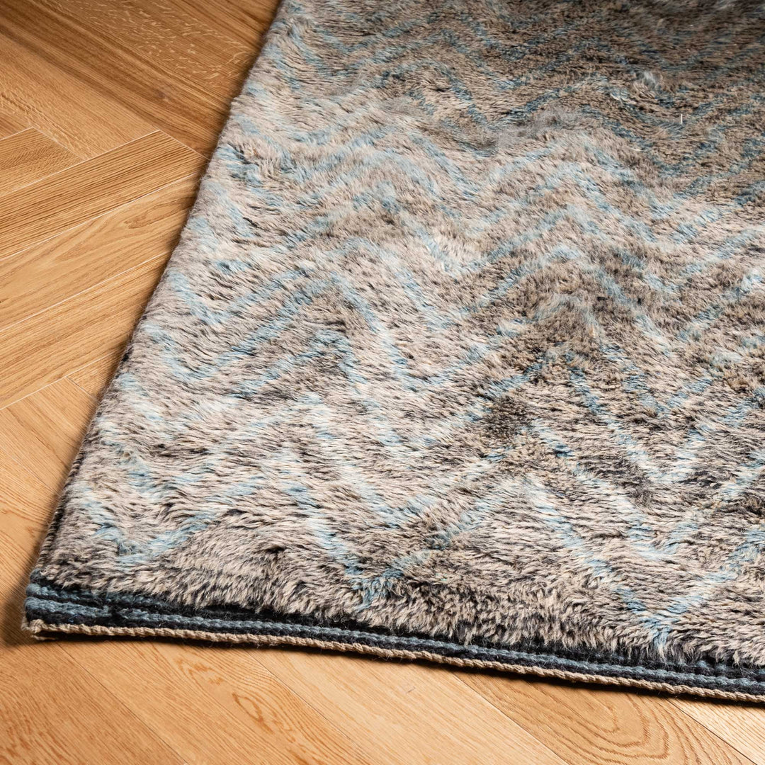 Zigzag Moroccan wool rug with chevron patterns on wooden floor, perfect for boho and modern interiors. Handmade, durable, and stylish.