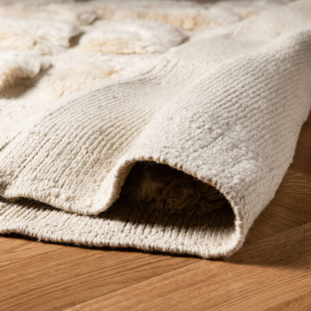 Close-up of a white check grid Moroccan wool rug on wooden floor, highlighting plush texture and handmade Berber craftsmanship.