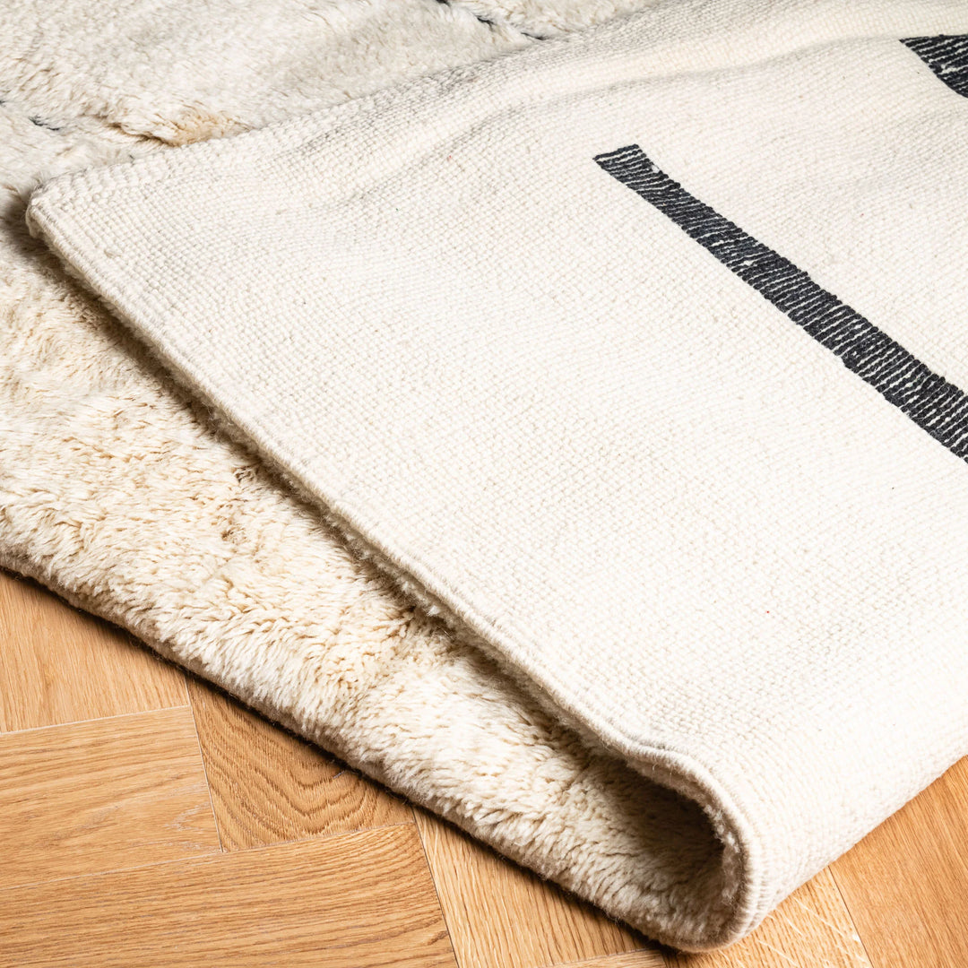 Handwoven modern abstract Beni Mrirt Moroccan wool rug with black lines on ivory, ideal for contemporary boho decor.