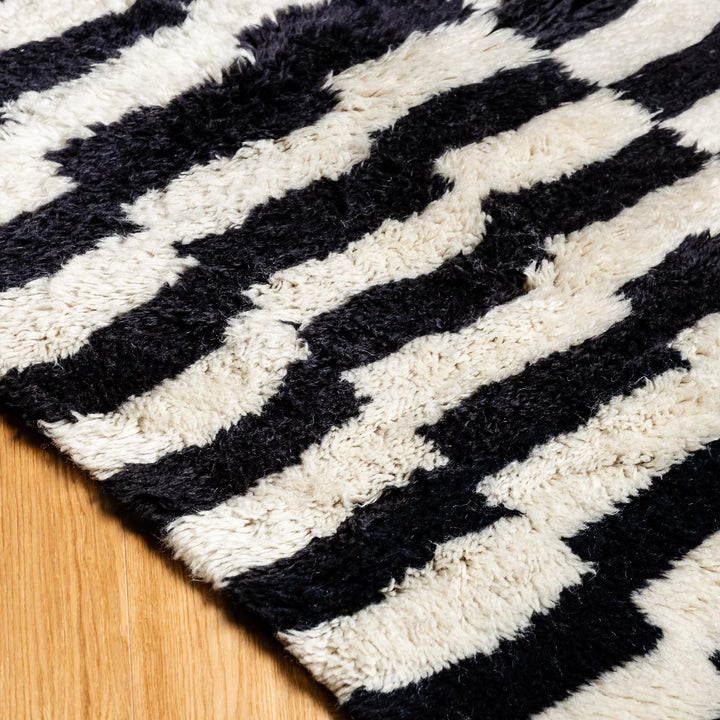 Black and white Moroccan runner rug with zigzag pattern on wooden floor, handcrafted from wool, perfect for hallways and entryways.