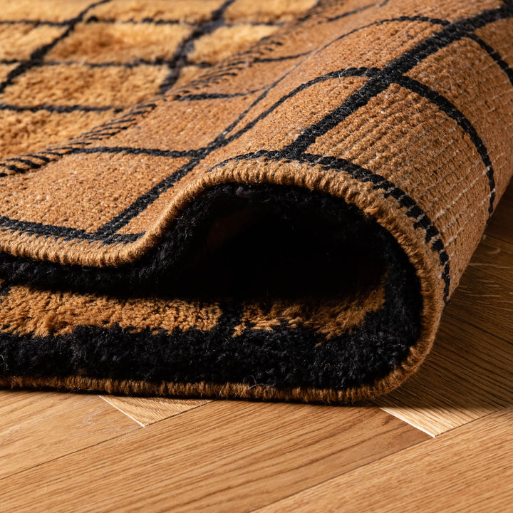 Close-up of a handwoven Moroccan runner rug with a black grid pattern, showcasing texture and craftsmanship on hardwood floor.
