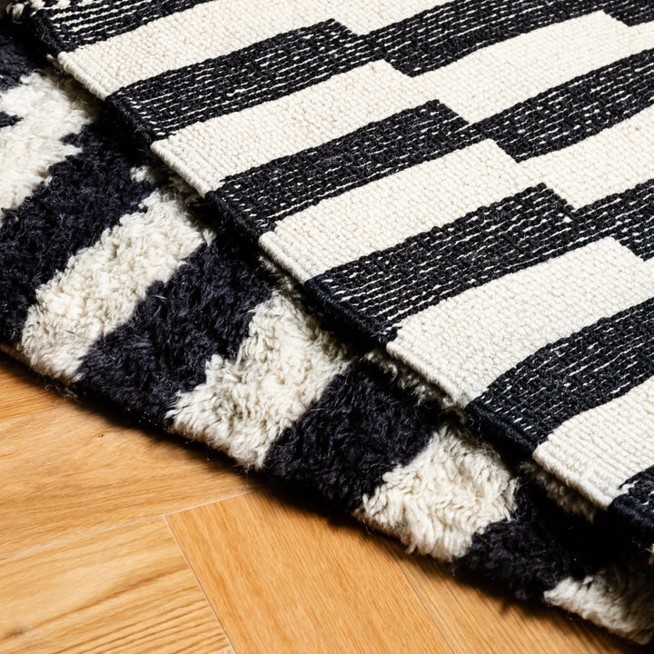 Close-up of black and white striped handwoven Moroccan runner rug on wooden floor.