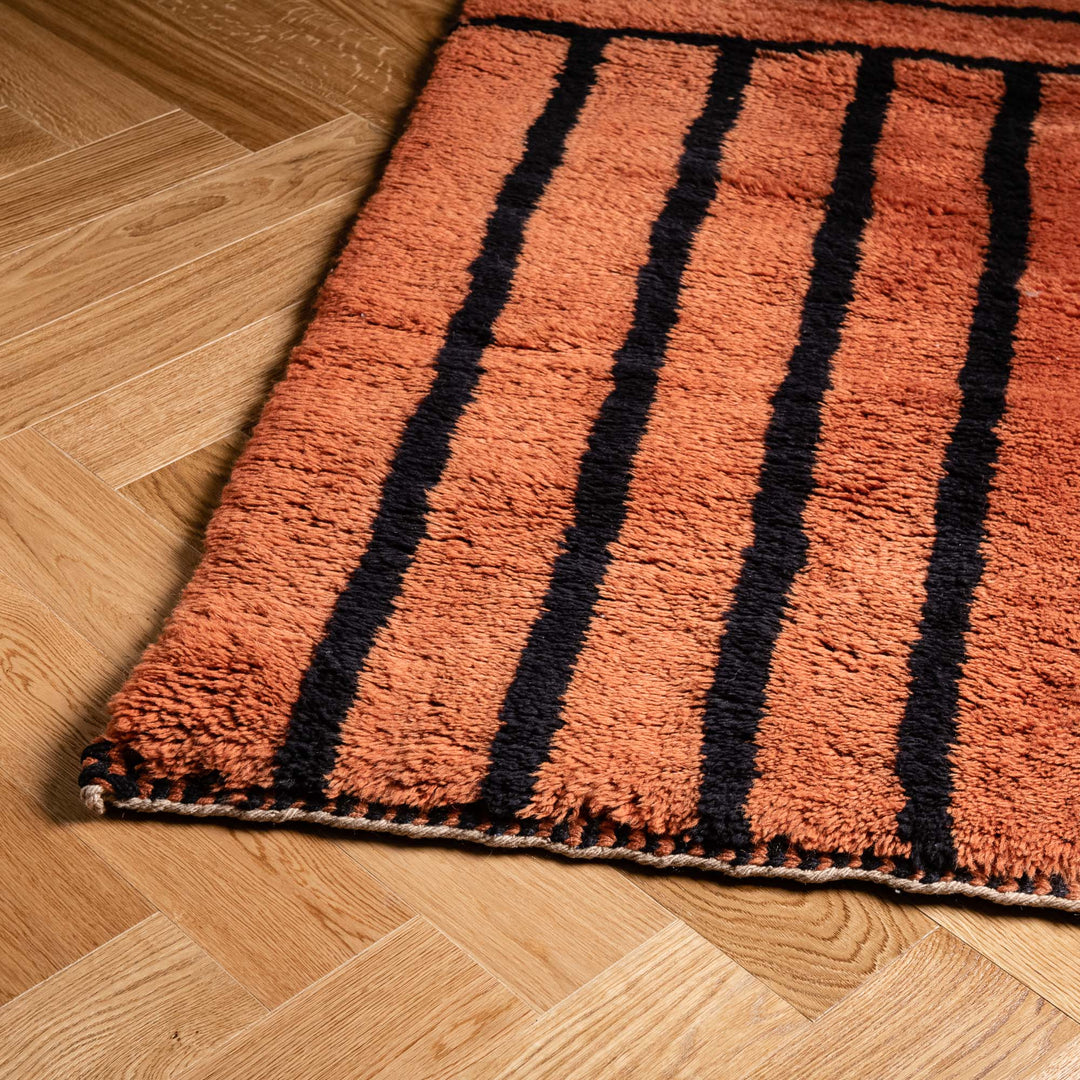 Handwoven Moroccan Runner Rug with black stripes, crafted with 100% wool, on a wooden floor, showcasing traditional Berber design.