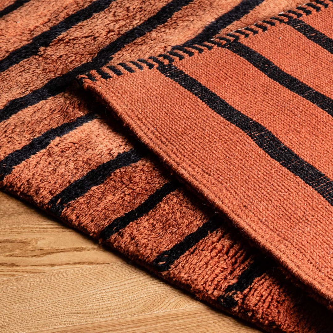 Handwoven Moroccan runner rug with black stripes on natural wool, showcasing artisanal craftsmanship and traditional Berber patterns.