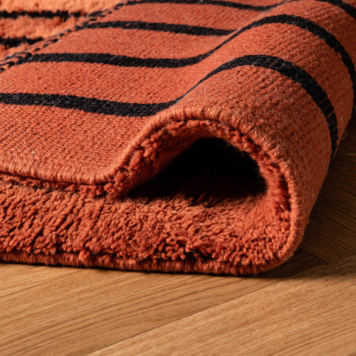 Close-up of a handwoven Moroccan runner rug in orange and black, showcasing thick texture, perfect for hallways or entryways.