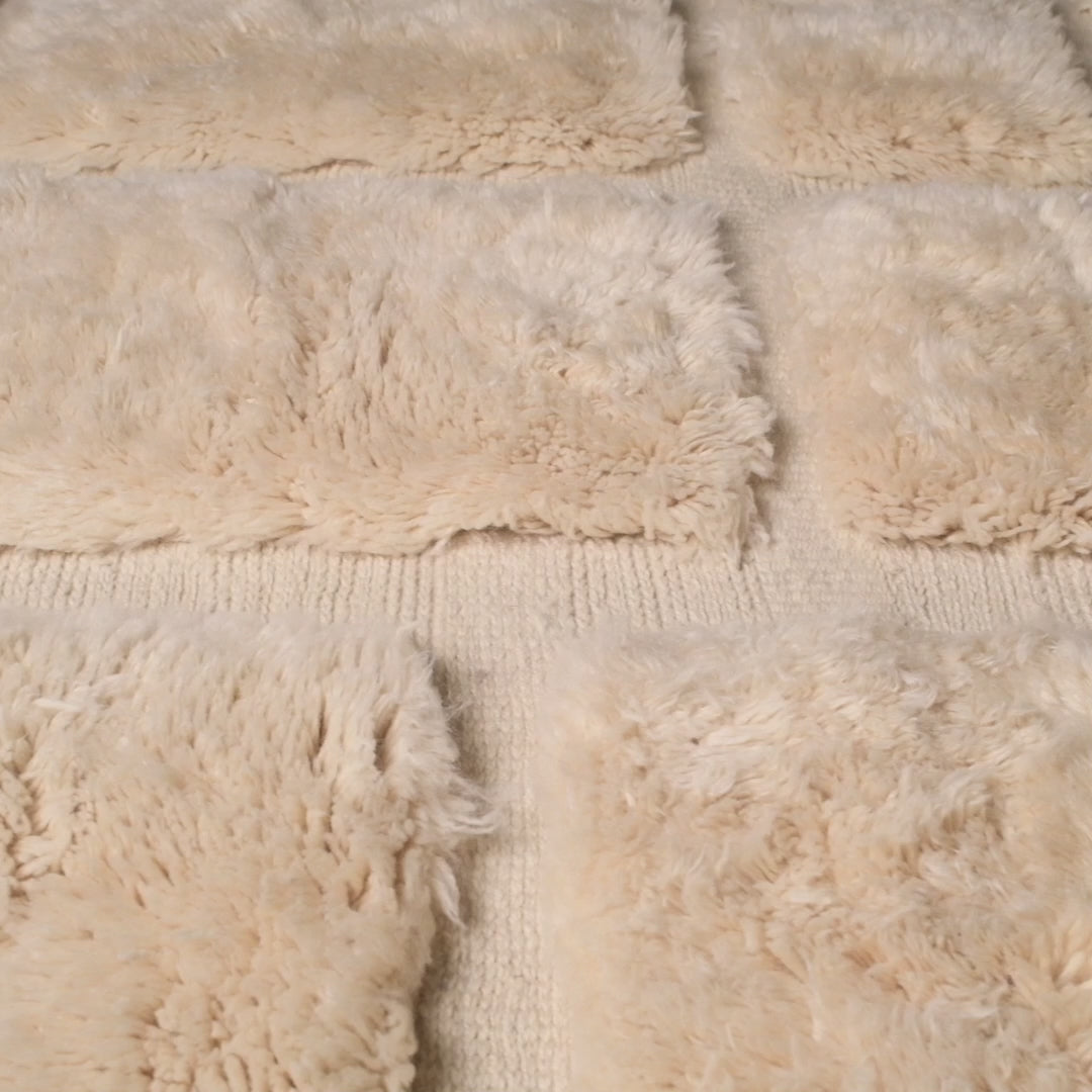 Close-up view of a handmade white Moroccan wool rug with a check grid pattern, crafted by Berber artisans. Ideal for minimalist homes.