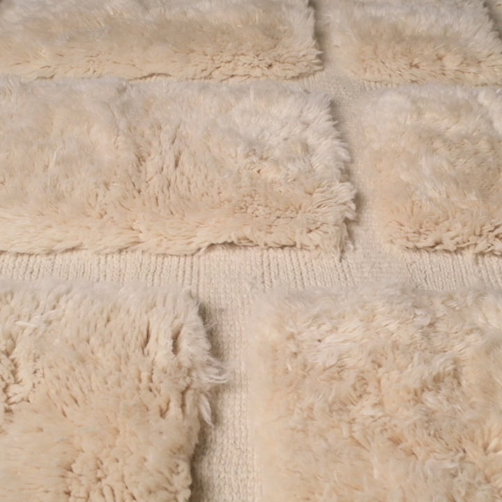 Close-up view of a handmade white Moroccan wool rug with a check grid pattern, crafted by Berber artisans. Ideal for minimalist homes.