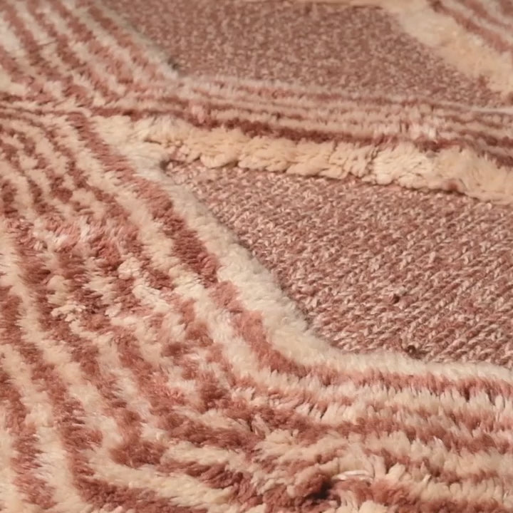 Close-up of a handmade Moroccan Beni Mrirt rug with intricate diamond and zigzag pattern in rose and clay tones.