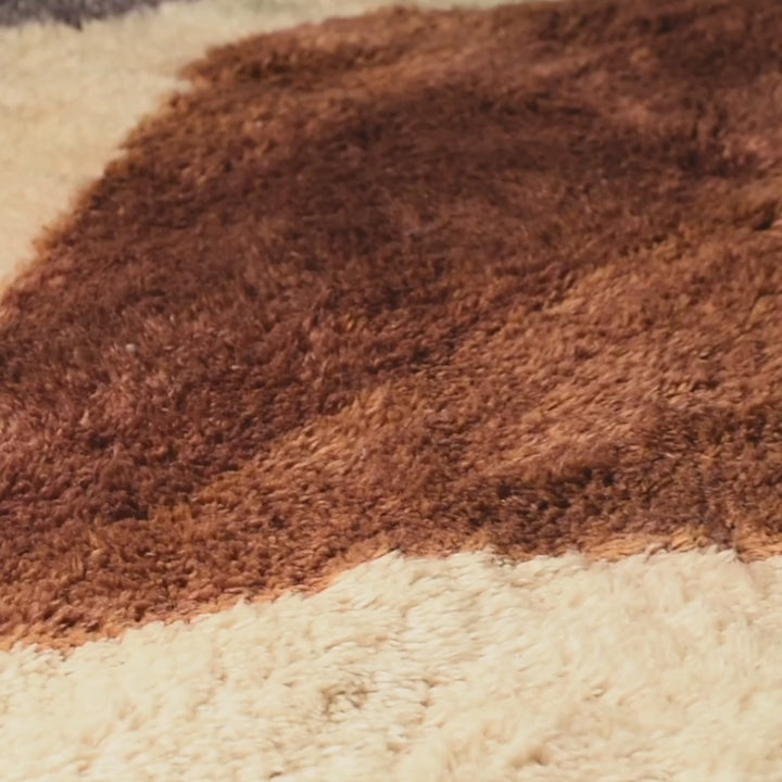 Close-up of handmade brown and cream wool Moroccan rug with geometric design.
