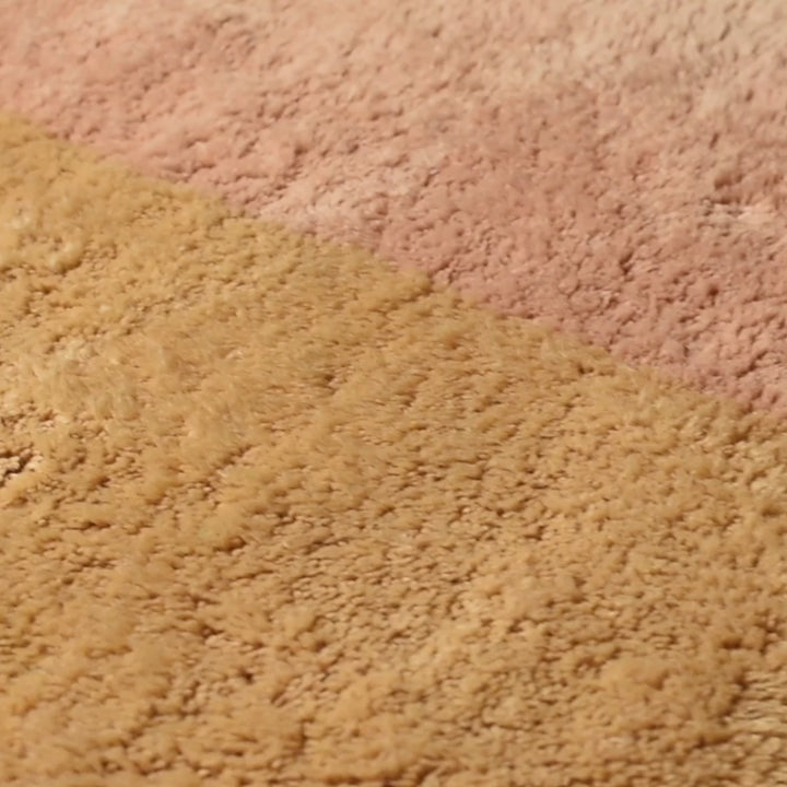 Close-up of a handwoven Moroccan wool rug in pink and beige tones, showcasing intricate berber patterns. Perfect for any elegant space.