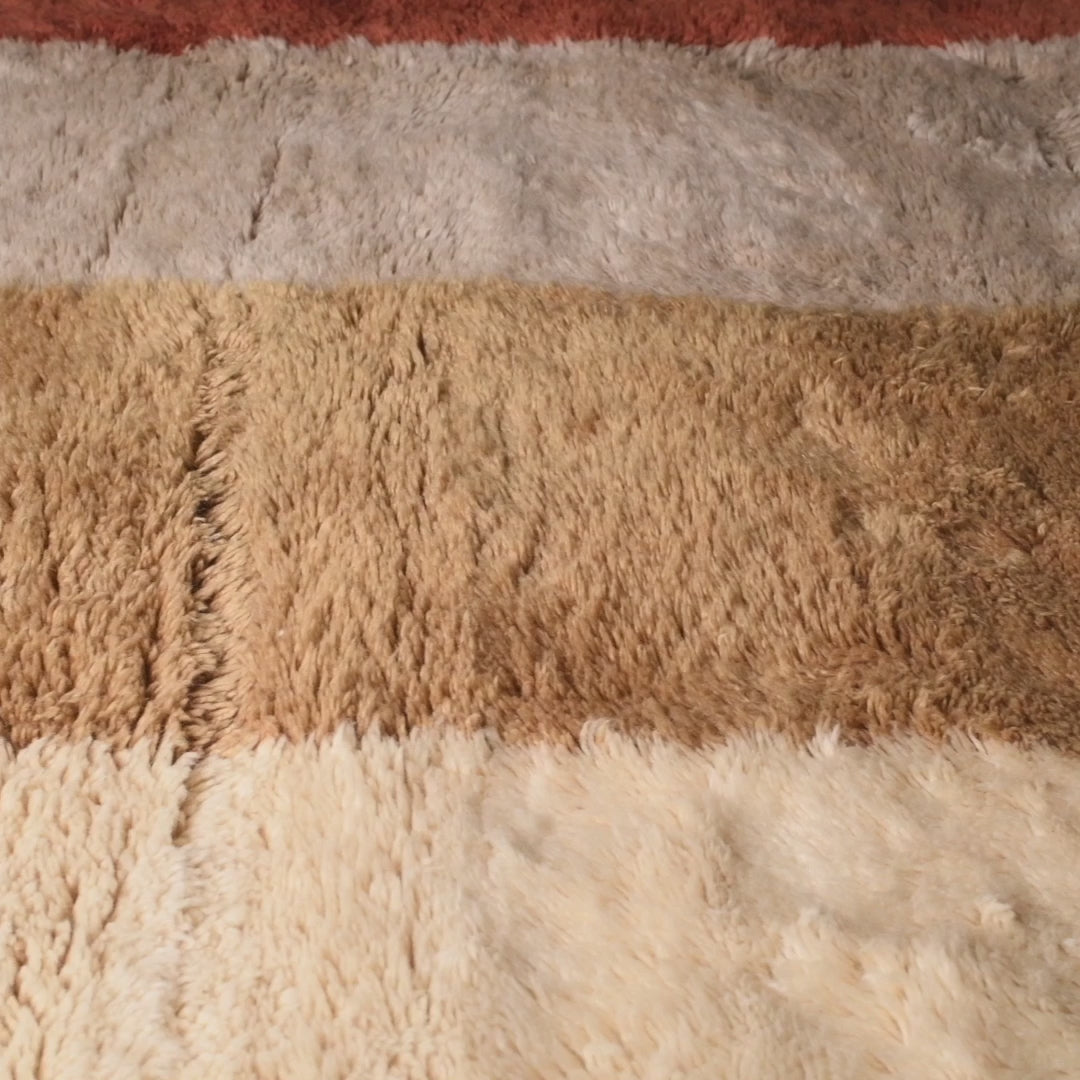 Modern abstract Moroccan wool rug in terracotta, ochre, and beige tones, showcasing a luxurious texture and artistic design.