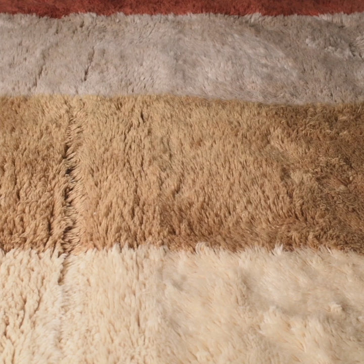 Modern abstract Moroccan wool rug in terracotta, ochre, and beige tones, showcasing a luxurious texture and artistic design.