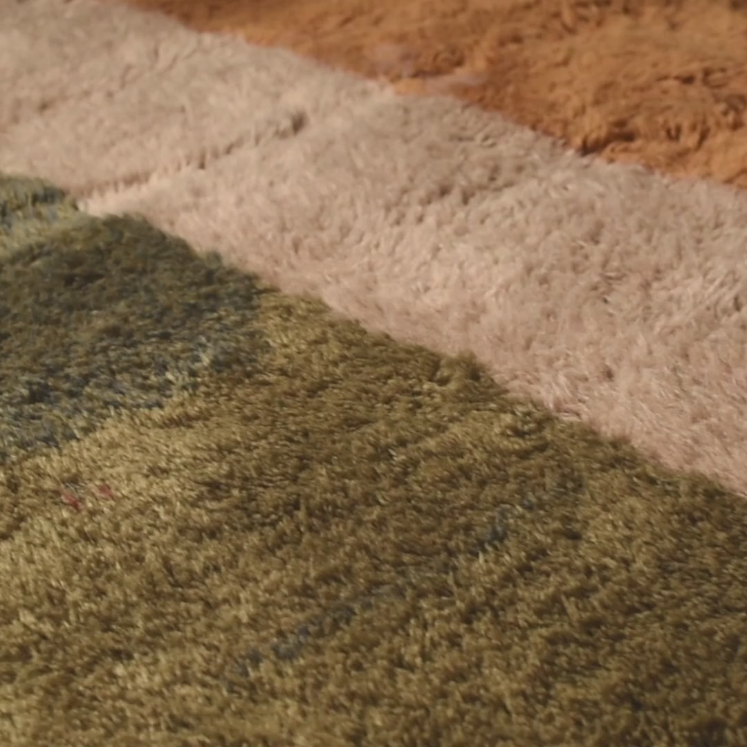 Close-up of a handmade Moroccan wool Beni Mrirt rug with earthy color blocks in amber, ivory, olive, and charcoal.
