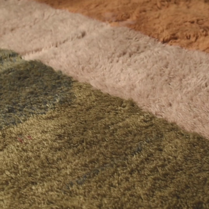 Close-up of a handmade Moroccan wool Beni Mrirt rug with earthy color blocks in amber, ivory, olive, and charcoal.