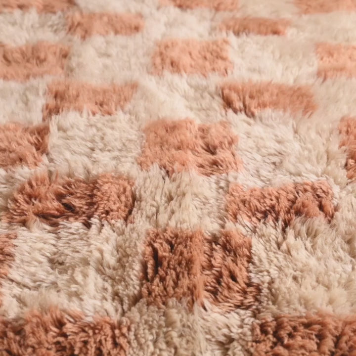 Close-up of a handcrafted checkered Moroccan Berber rug featuring a plush shag texture and warm colors, ideal for cozy interiors.