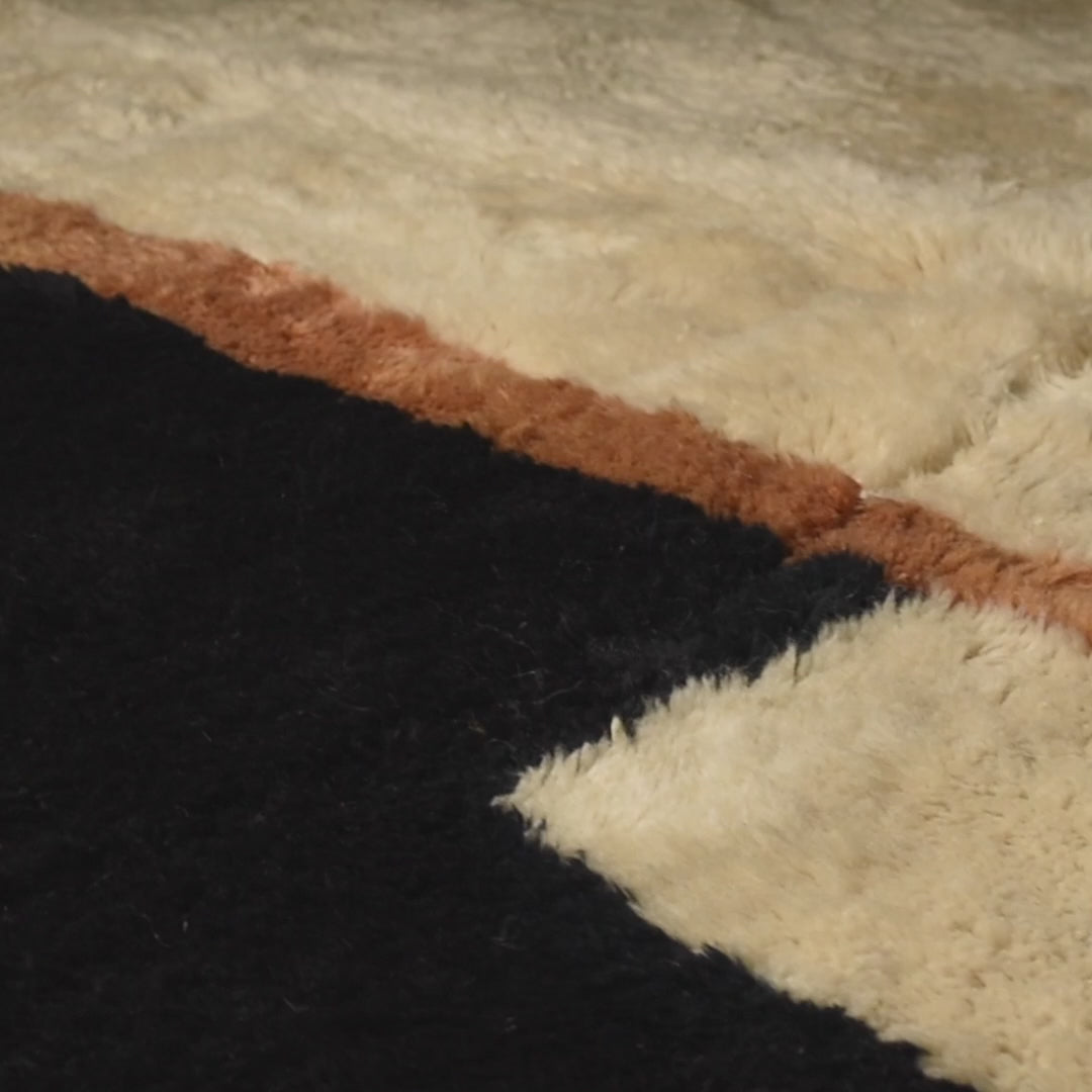 Close-up of modern Moroccan Beni Mrirt rug with black, ivory, and amber geometric blocks; wool texture for contemporary interiors.