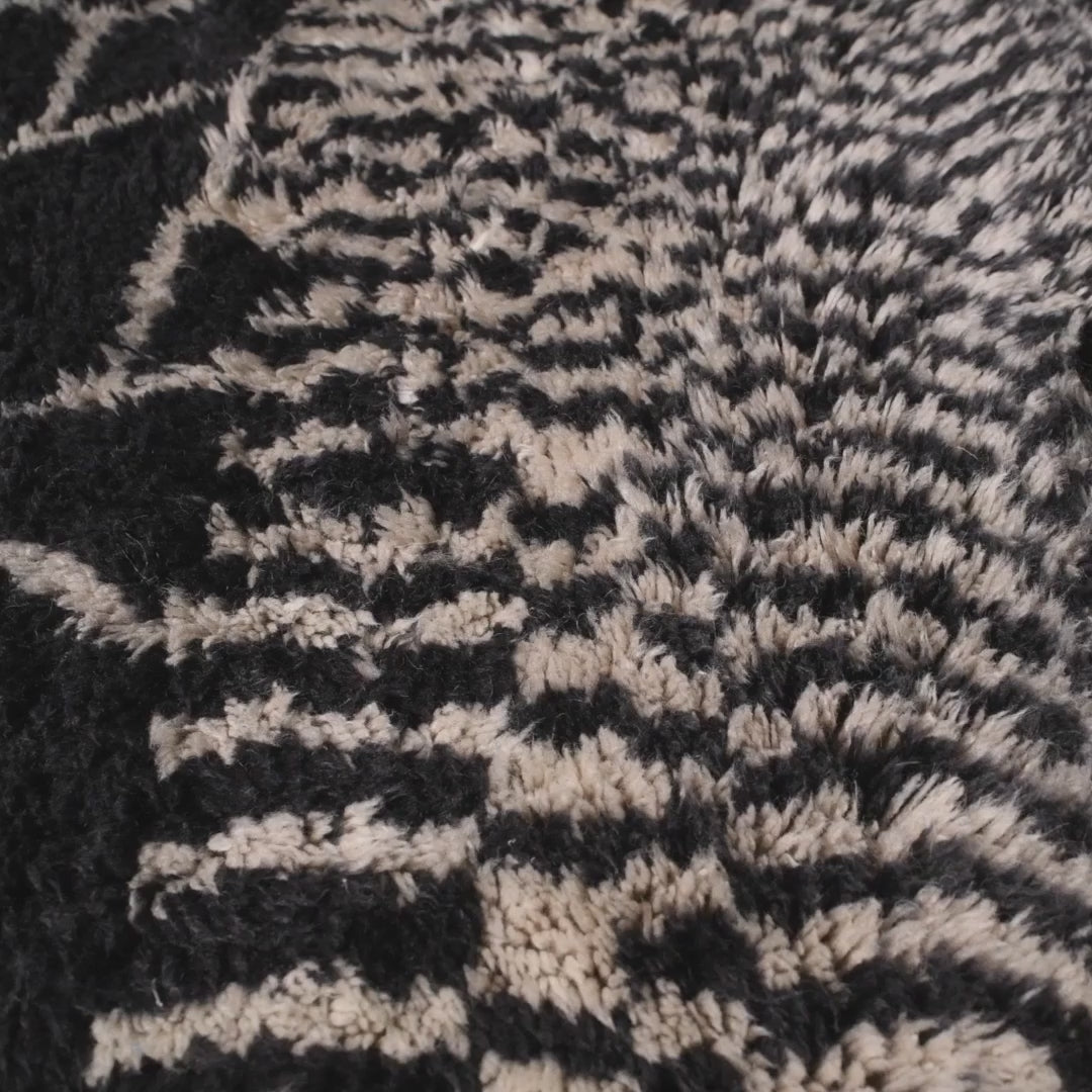 Handmade Moroccan black and white wool rug with abstract geometric design, perfect for contemporary and artistic spaces.