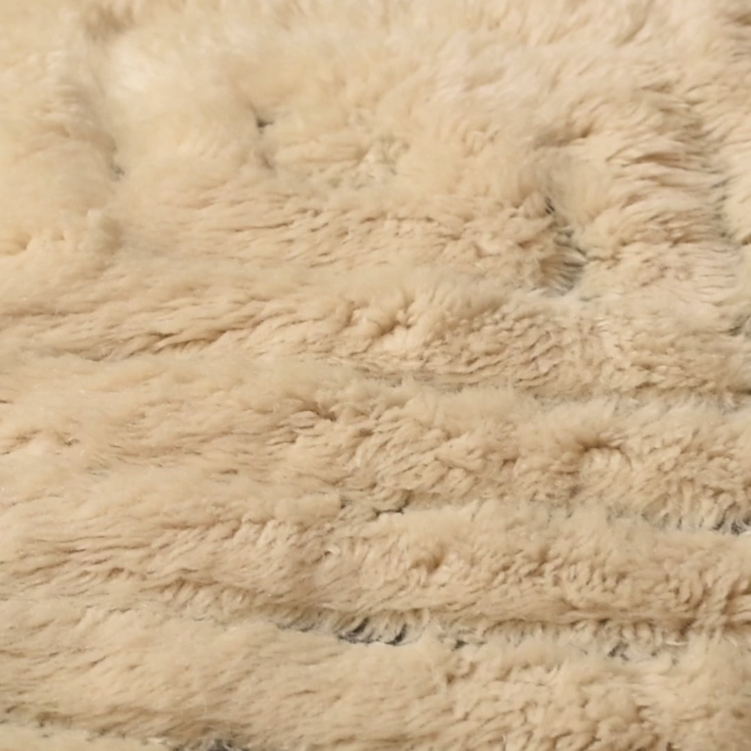 Close-up of textured beige Moroccan wool rug showing plush, handcrafted detail and traditional craftsmanship.