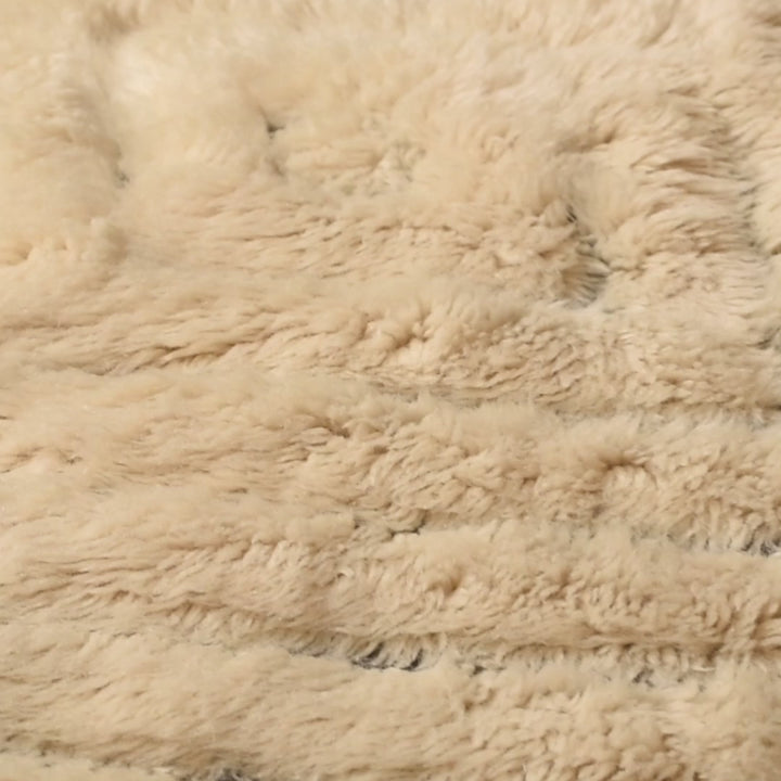 Close-up of textured beige Moroccan wool rug showing plush, handcrafted detail and traditional craftsmanship.