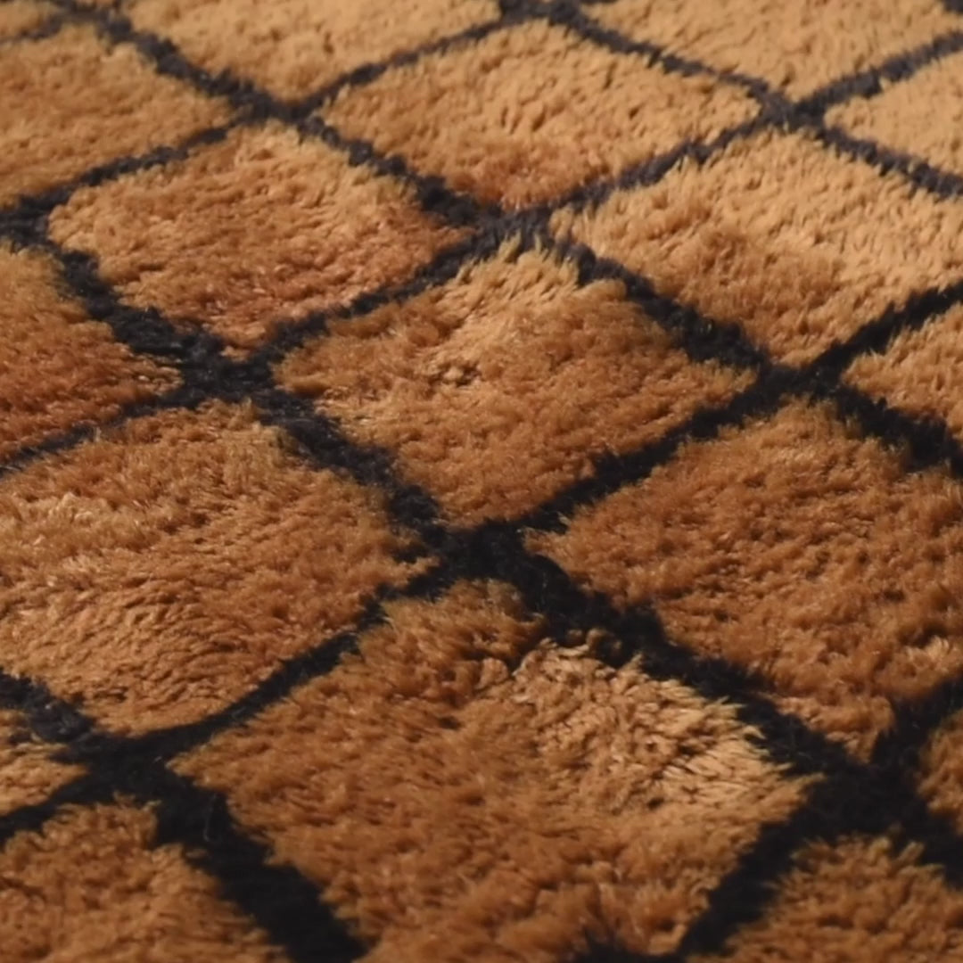 Close-up of a handcrafted Moroccan runner rug with geometric patterns in brown and black, made from 100% natural wool.