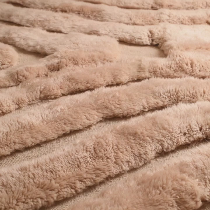 Close-up of a plush beige textile with a textured pattern, showcasing soft and thick fibers for home decor and comfort.